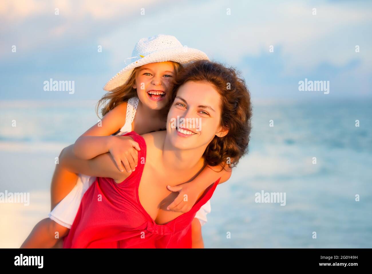Portrait von glücklicher Mutter und kleiner Tochter am sonnigen Strand auf den Malediven im Sommerurlaub. Familie am Strand Konzept. Stockfoto