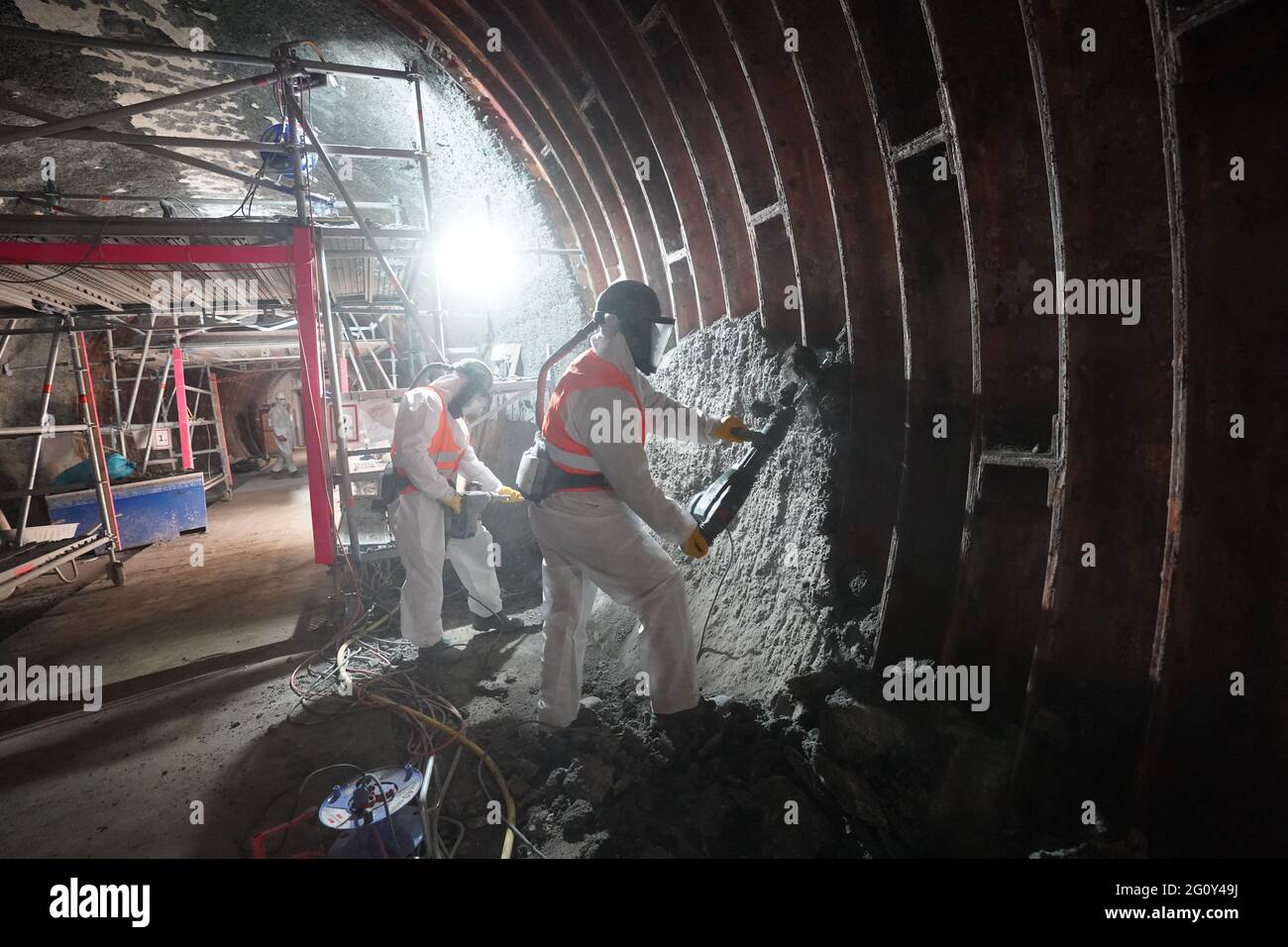 03. Juni 2021, Hamburg: Im Westrohr des Alten Elbtunnels arbeiten Arbeiter mit Atemmasken und Schutzanzügen. Es wird wahrscheinlich noch fünf Jahre dauern, bis Hamburg den Alten Elbtunnel wieder vollständig in Besitz nehmen kann. Nach der Wiedereröffnung der Oströhre vor zwei Jahren sollte dann auch die Weströhre, die seit 2019 repariert wird, fertig sein. Die Gesamtkosten für das jahrzehntelange Renovierungsprojekt sollten sich bis dahin auf 114 Millionen Euro belaufen, wie Finanzsenator Dressel bei einem Rundgang durch die Bauarbeiten sagte. (To dpa 'Renovierung des Alten Elbtunnels: West Tub Stockfoto