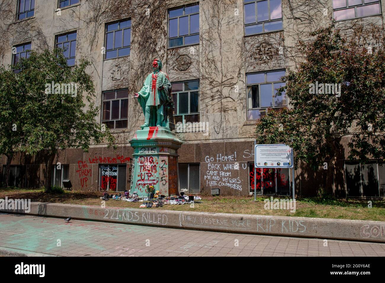 Toronto, Kanada. Juni 2021. Die Statue wurde in roter Farbe übergossen.215 Schuhe wurden um die Statue von Egerton Ryerson auf dem Campus der Ryerson University als Gedenkstätte gelegt und nach der Entdeckung von 215 Leichen von Studenten aus Wohnschulen in Kamloops, British Columbia, an einem Massengrab verwüstet. Egerton Ryerson war ein ursprünglicher Architekt des Wohnschulsystems. (Foto: Shawn Goldberg/SOPA Images/Sipa USA) Quelle: SIPA USA/Alamy Live News Stockfoto