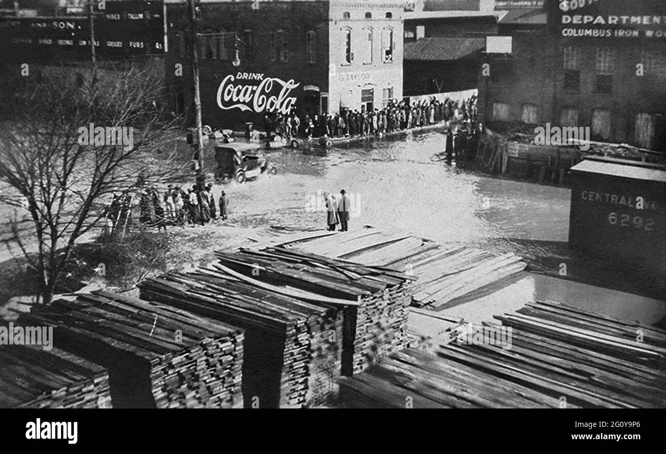 Oldtimer, die durch überflutete Straßen in Columbus, Georgia, fahren, während die Zuschauer von trockenem Boden aus zusehen. Der Chattahoochee River, der an Uptown Columbus entlang fließt, überflutete Mitte Februar 1900 seine Ufer. Stockfoto