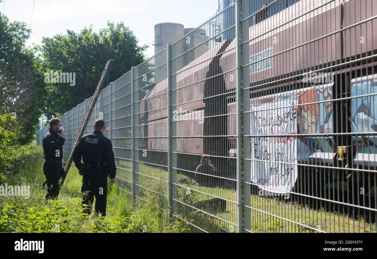 Wolfsburg, Deutschland. Juni 2021. Polizeibeamte stehen neben einem Kohlezug, der von Aktivisten besetzt ist, auf dem Gelände des VW-Kohlekraftwerks. Demonstranten der Aktionsgruppe "get off the Gas" besetzen seit heute früh das Kohlekraftwerk im Volkswagen-Werk in Wolfsburg. Quelle: Julian Stratenschulte/dpa/Alamy Live News Stockfoto