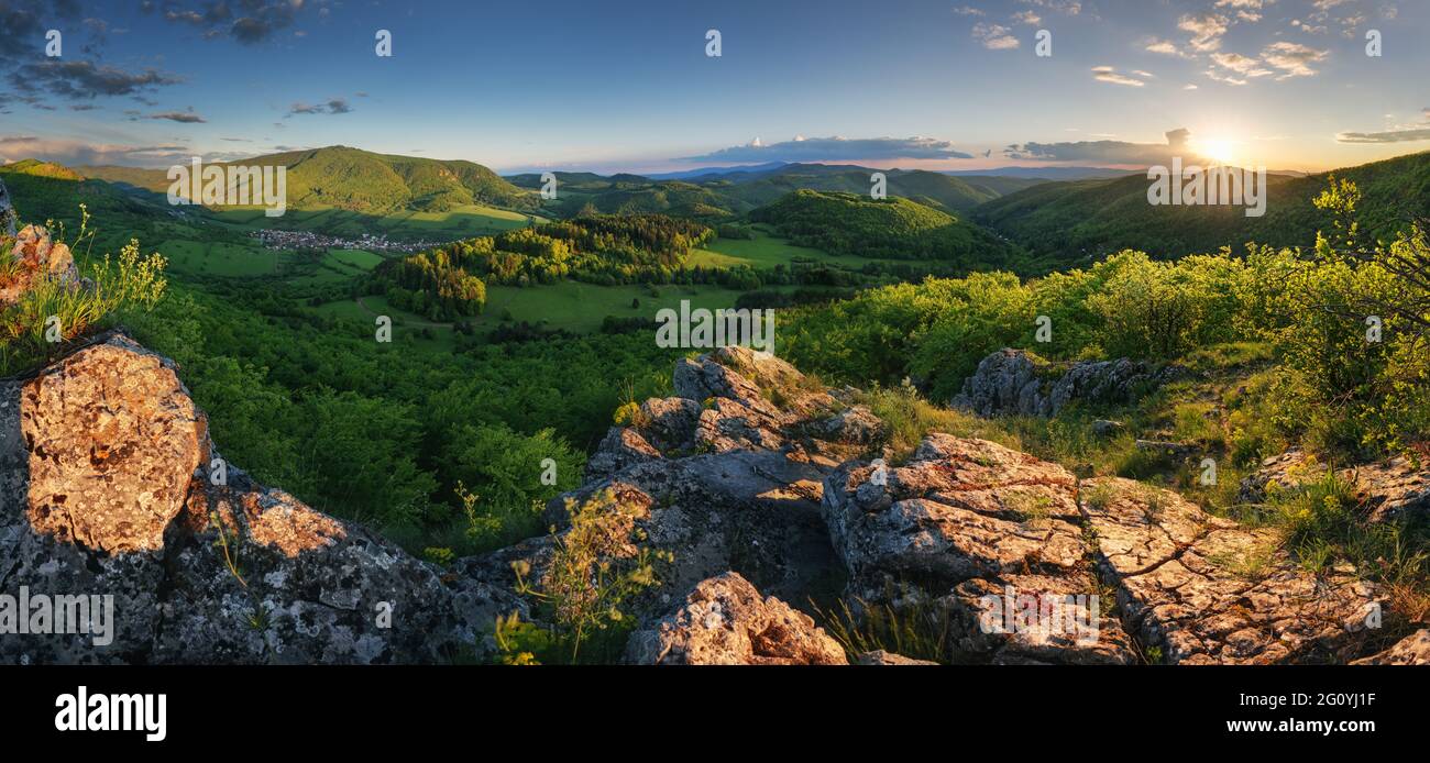 Grüne Frühlingsberglandschaft mit Sonne und Felsen - Panorama Stockfoto
