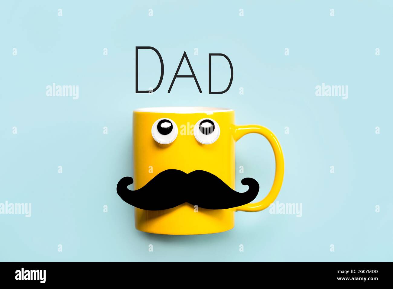 Happy Father's Day.Gelber Becher mit Schnurrbart und lustigen Augen, die mit dem Text Dad auf blauem Hintergrund aufschauen Stockfoto