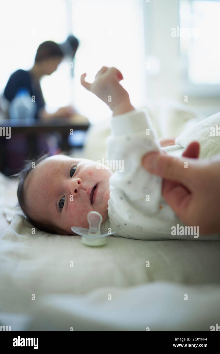 Neugeborenes, das im Bett liegt und einen ausgefallenen Schnuller hat Stockfoto