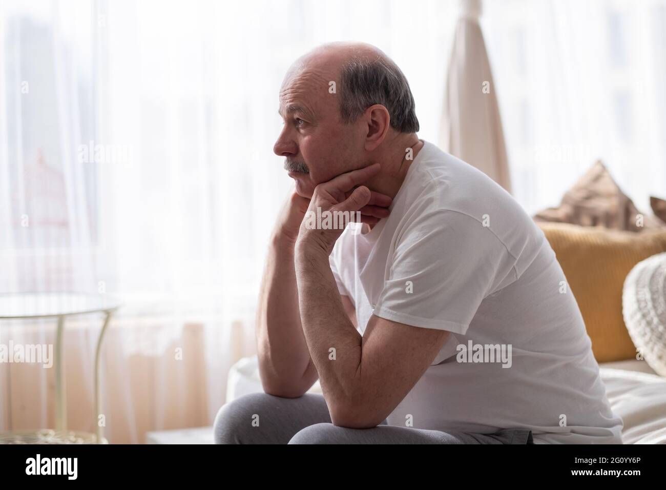 Traurig, älterer Mann mit dem Kopf in den Händen auf dem Bett zu Hause sitzen Stockfoto