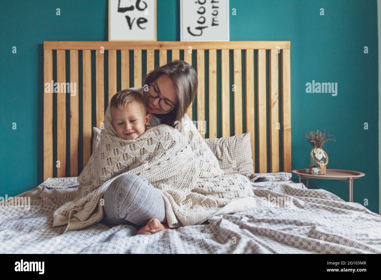 Mama und Kind haben Spaß im Schlafzimmer auf dem Bett unter dem Rohling Stockfoto