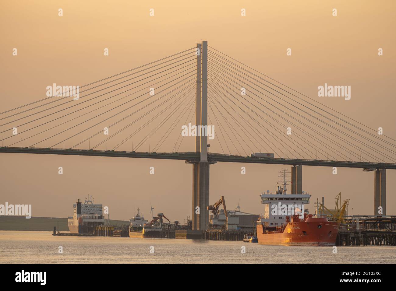 Schiffe, die an der Purfleet anlegen, docken mit der Dartford Bridge über die Themse bei Sonnenuntergang an Stockfoto
