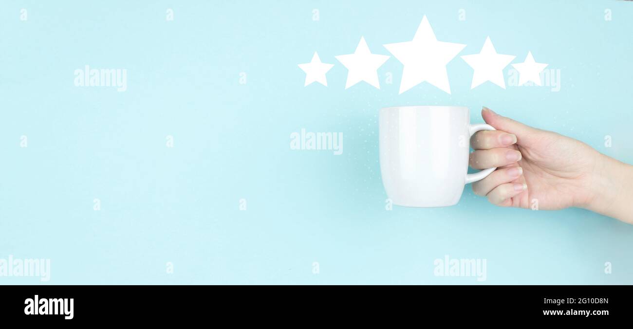Customer Experience Konzept. Mädchen Hand halten Morgen Kaffeetasse mit fünf Sternen 5 Rating-Zeichen-Symbol auf blauem Hintergrund. Bewertungsbewertung erhöhen und c Stockfoto