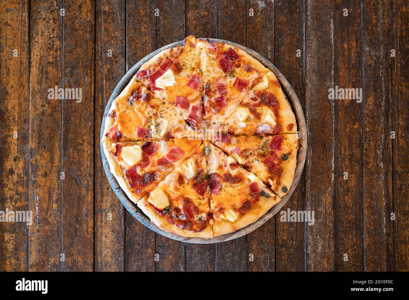 Hausgemachte, geräucherte hawaiianische Speck-BBQ-Pizza auf Holzplatte Stockfoto