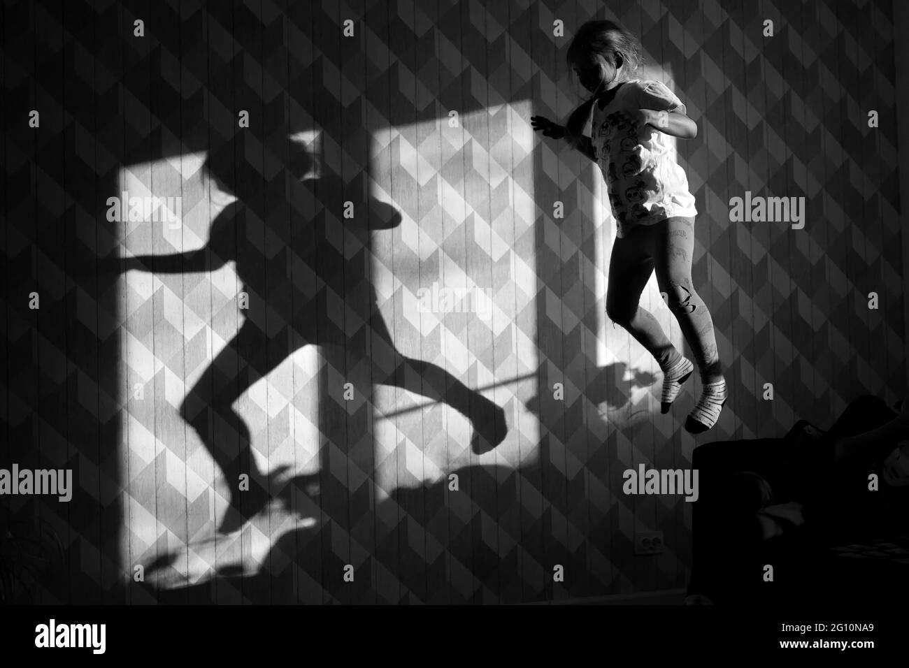 Mädchen springt vor die Wand und ihr Schatten ist auf der Wand Stockfoto