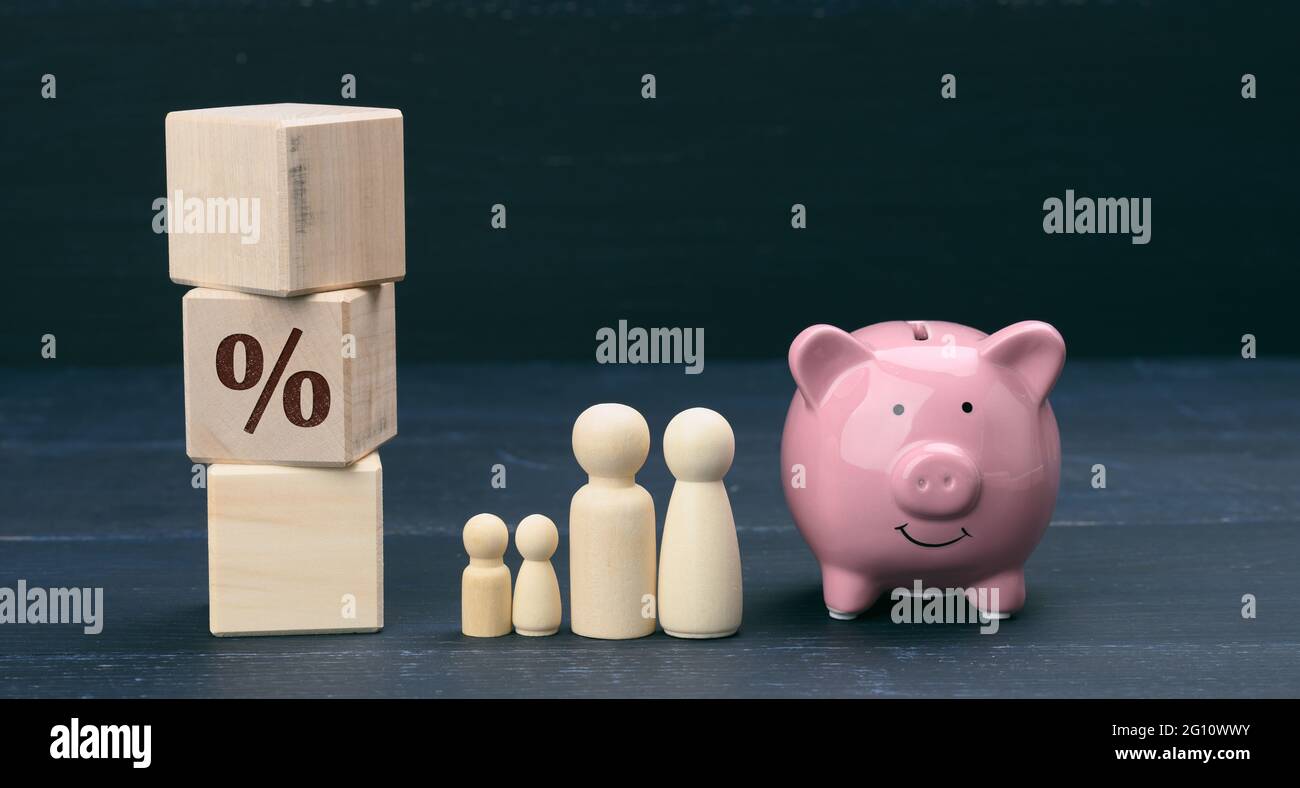 Hölzerne Familienfiguren und rosa Keramik Sparschwein, Sparkonzept, Budgetkontrolle. Langfristige Planung der Verteilung der Mittel für große Käuferzahlen Stockfoto