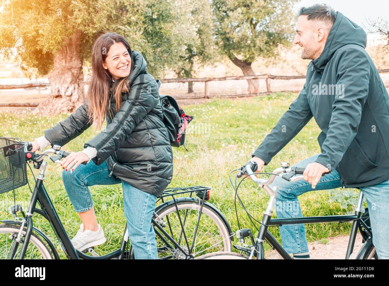 Junge Verlobte machen einen Spaziergang auf dem Land mit Fahrrädern - Freunde haben Spaß beim Fahrradfahren - warmes Flare auf der linken Seite Stockfoto