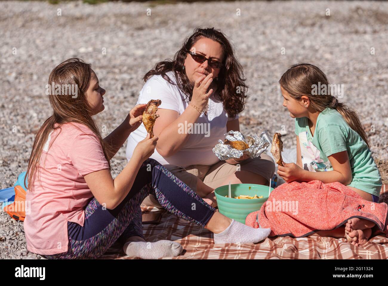 Alleinerziehende Mutter mit ihren zwei kleinen Töchtern, die während einer Wanderung bei einem Raststopp essen Stockfoto