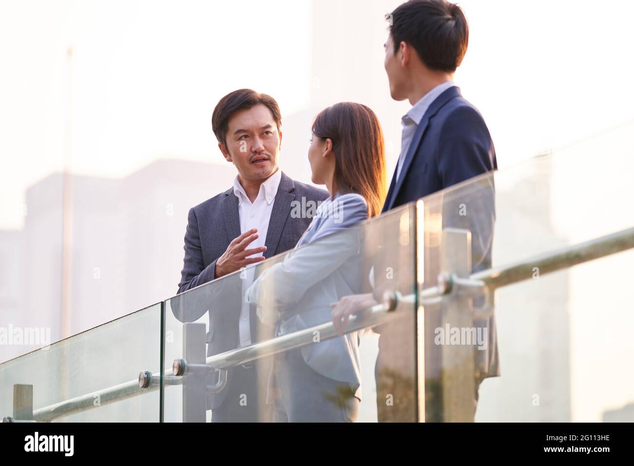 Drei glückliche asiatische Geschäftsleute unterhalten sich im Gespräch über Geschäfte im Freien Stockfoto