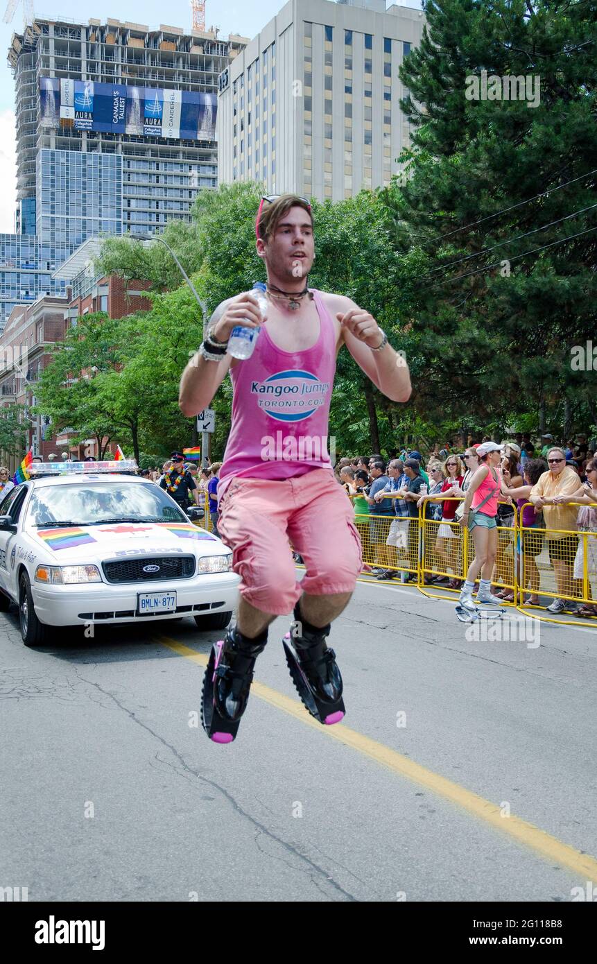 Szenen der Toronto Pride Parade: Marcher in rosa gekleidet springt bei einer Pride Parade vor einem Polizeiwagen in die Luft. Stockfoto