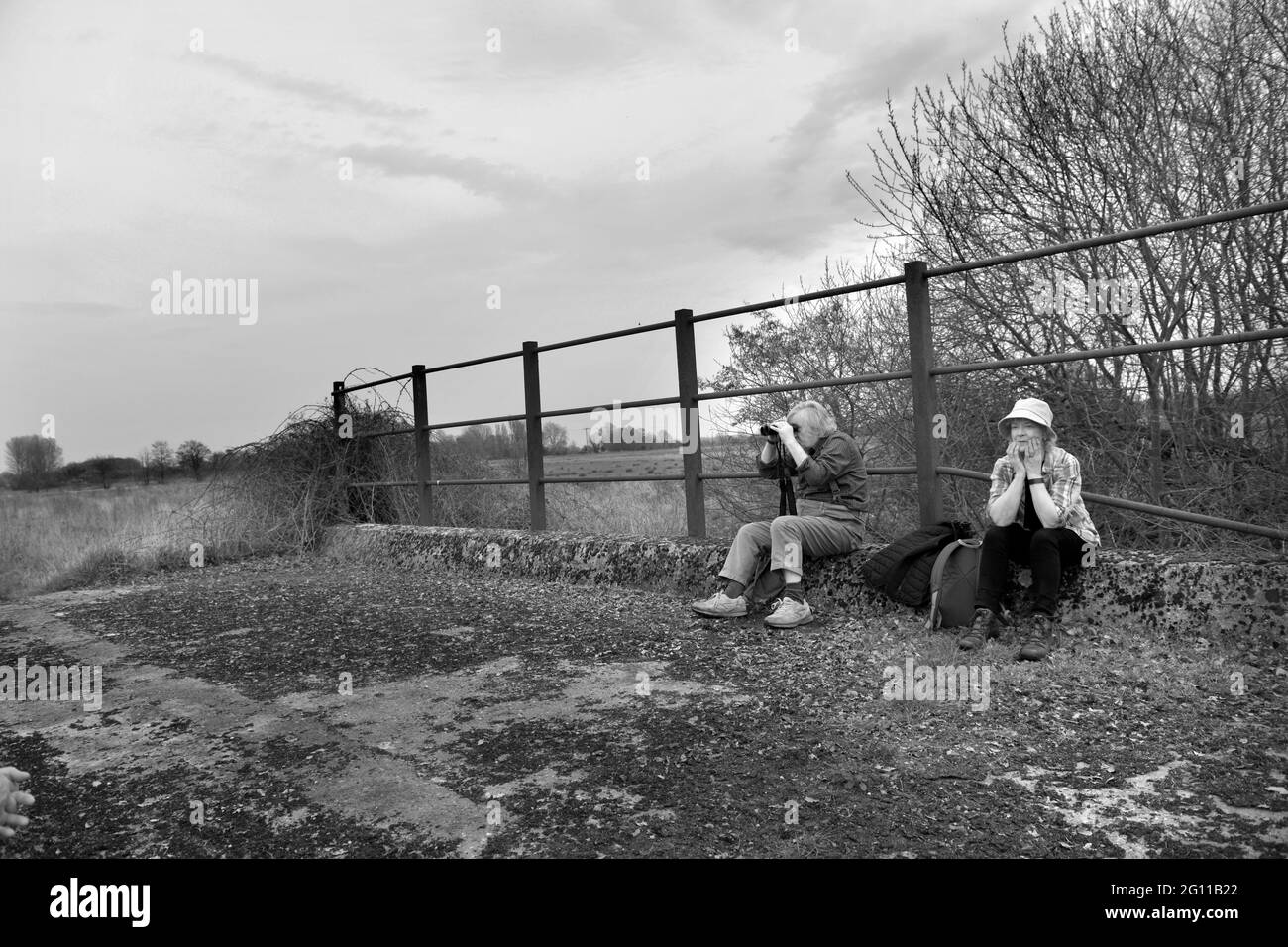 Mann und Frau sitzen auf der alten redundanten Eisenbahnbrücke ellingham norfolk england Stockfoto