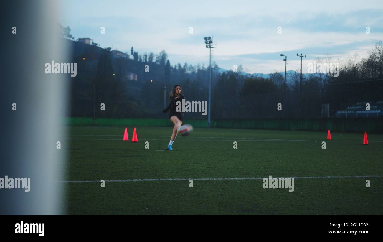 Junge Fußballspielerin tritt den Ball vom Elfmeter in das Tor. Blick von der Rückseite des Tores. Stockfoto