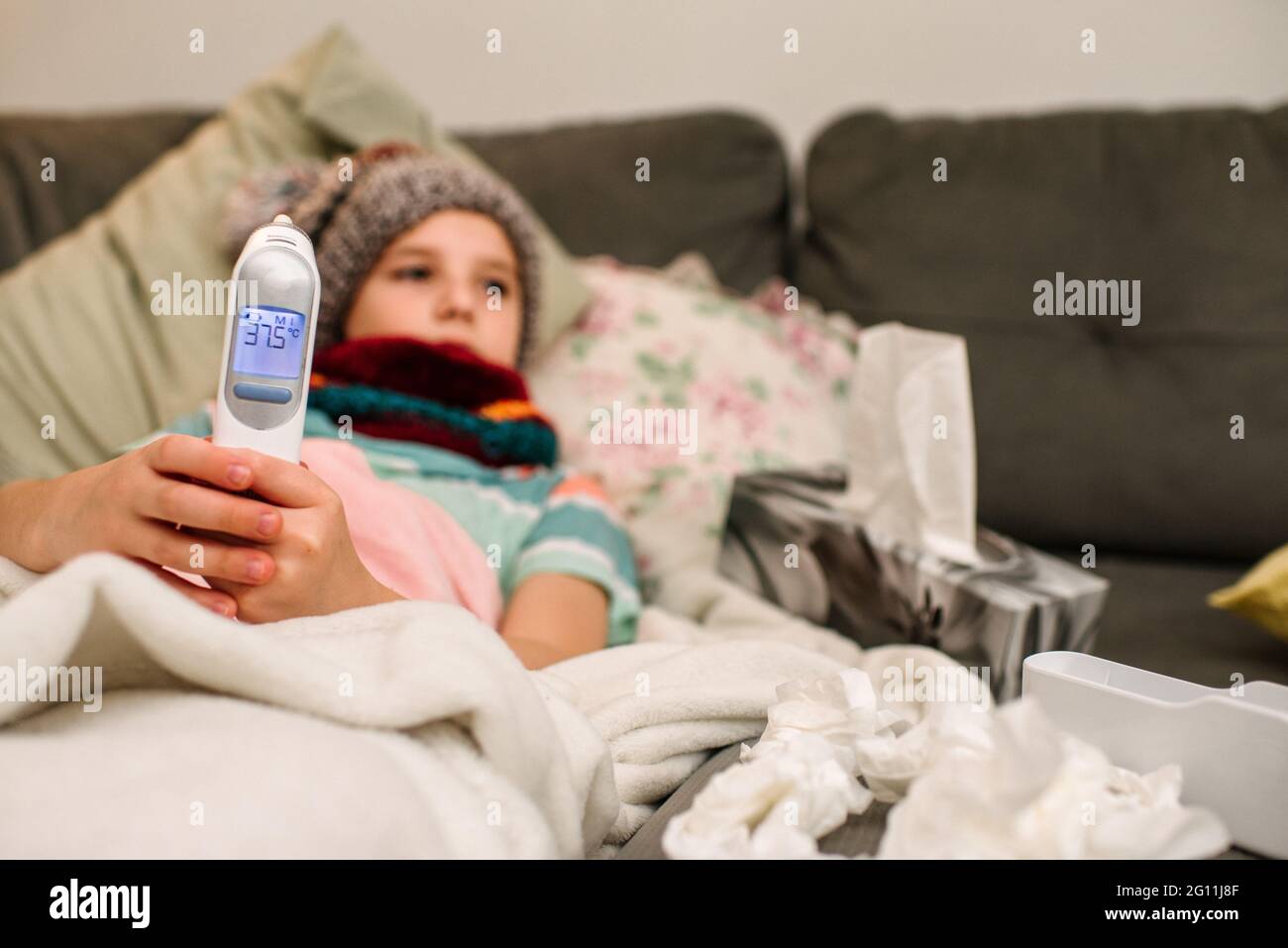 Kanada, Ontario, Junge in Strickmütze mit elektronischem Thermometer auf dem Sofa Stockfoto