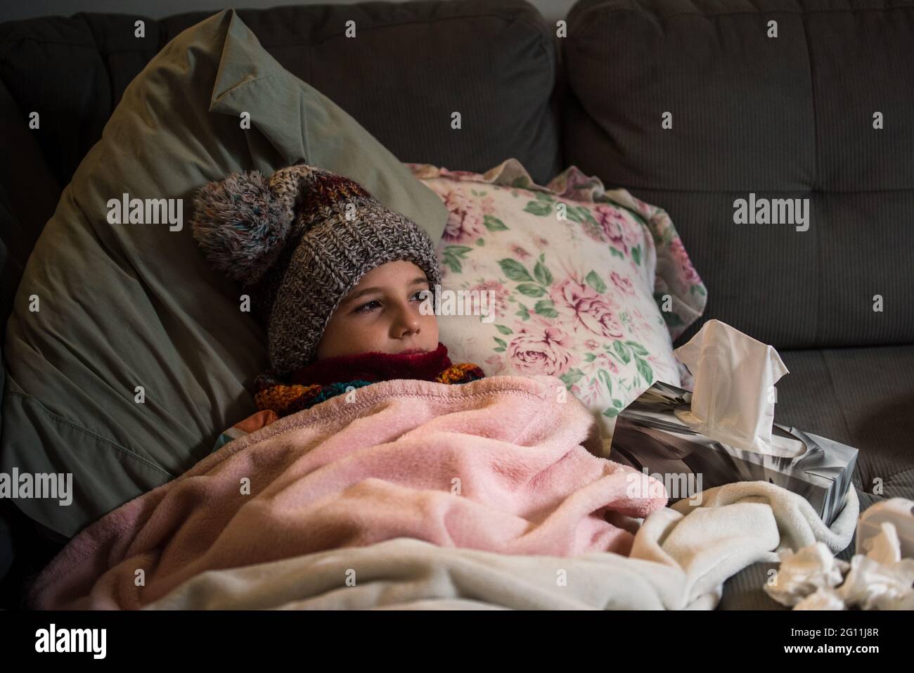 Kanada, Ontario, Junge in Strickmütze auf Sofa mit Decke bedeckt liegen Stockfoto