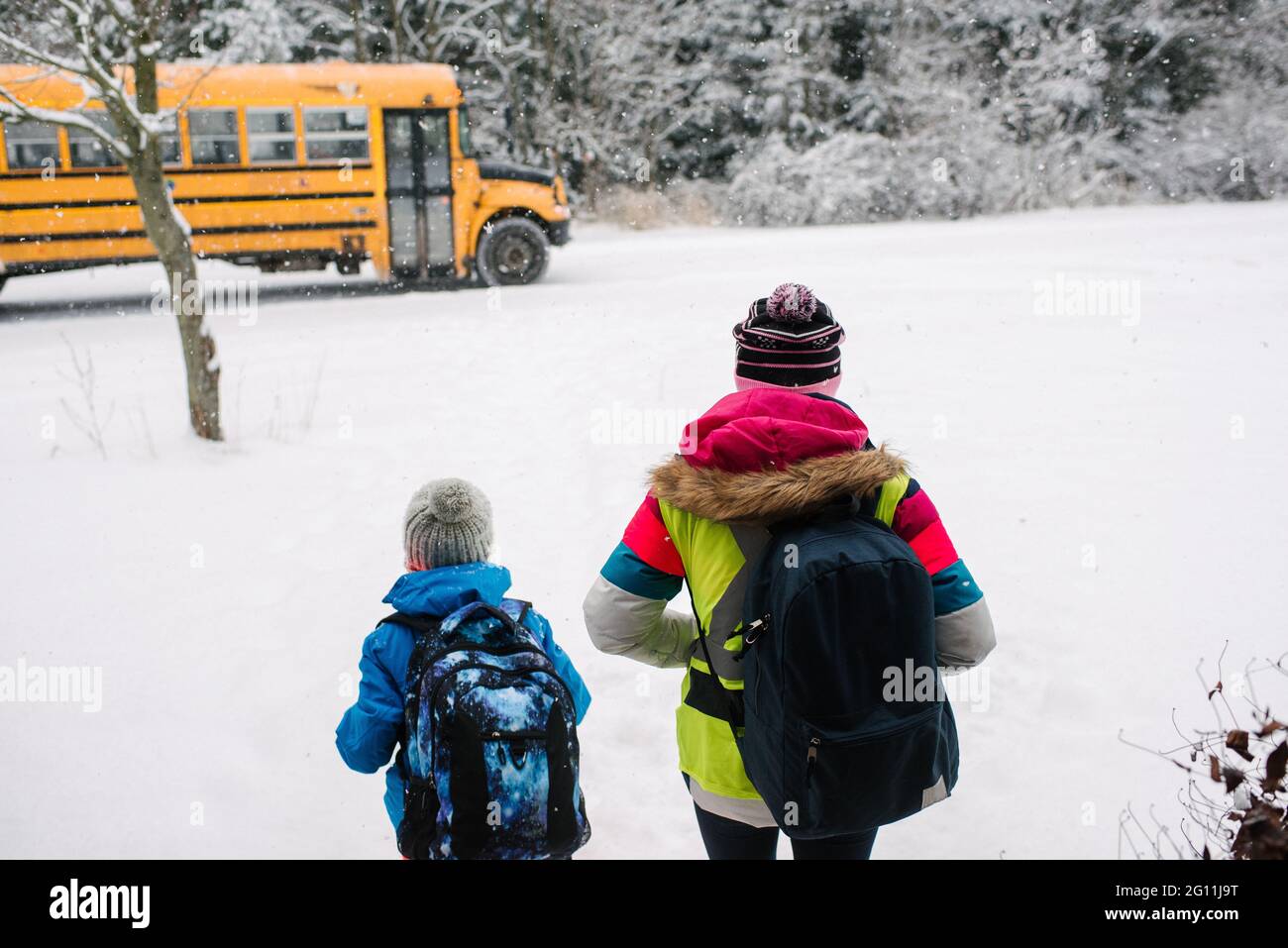 Kanada, Ontario, Rückansicht von Kindern, die im Schnee in Richtung Schulbus gehen Stockfoto