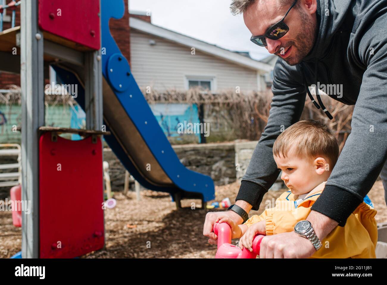 Kanada, Kingston, Vater mit Sohn, der auf dem Spielplatz ein kleines Fahrrad fährt Stockfoto