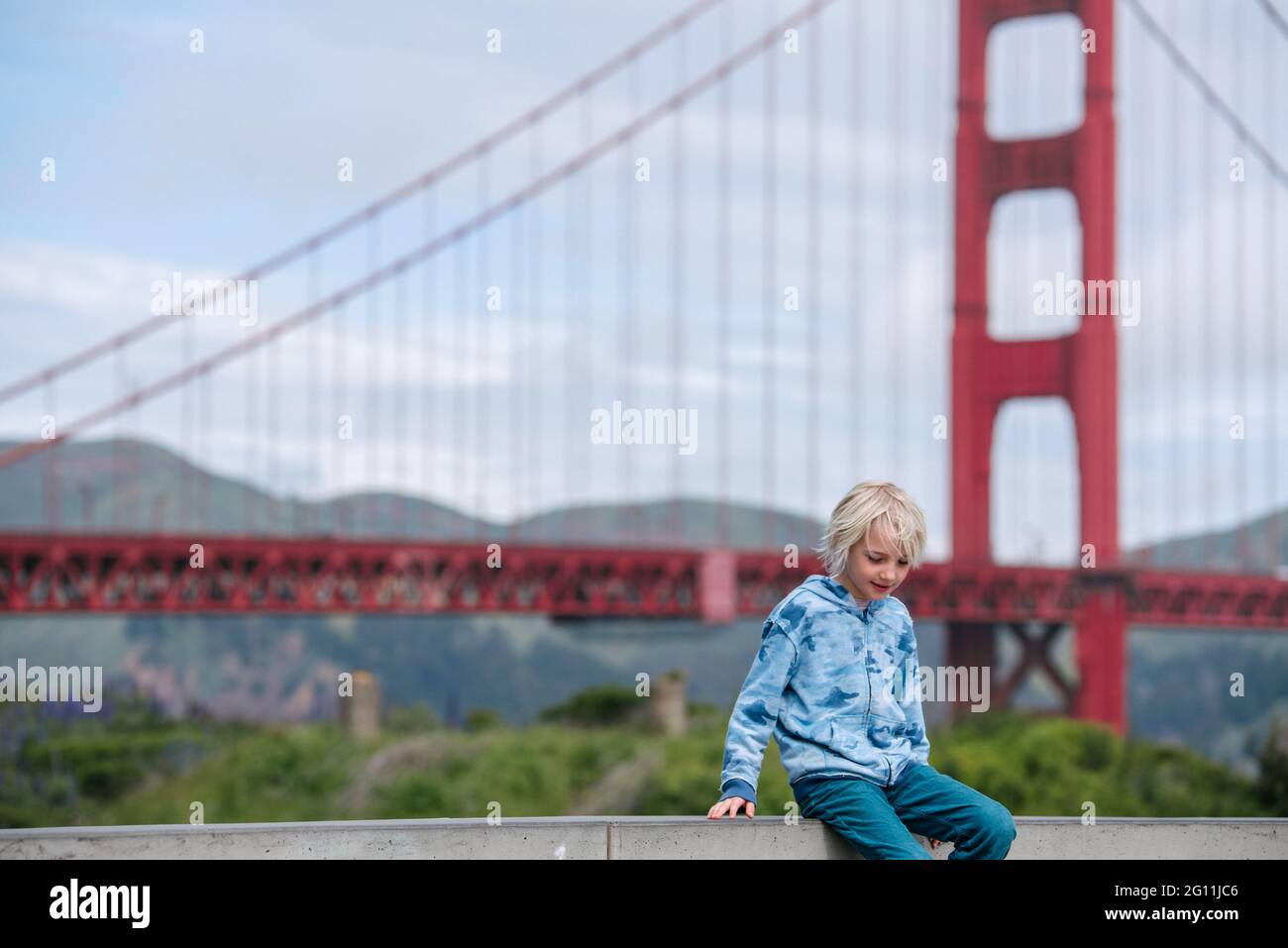 USA, CA, San Francisco, Junge sitzt an einer Wand in der Nähe der Golden Gate Bridge Stockfoto