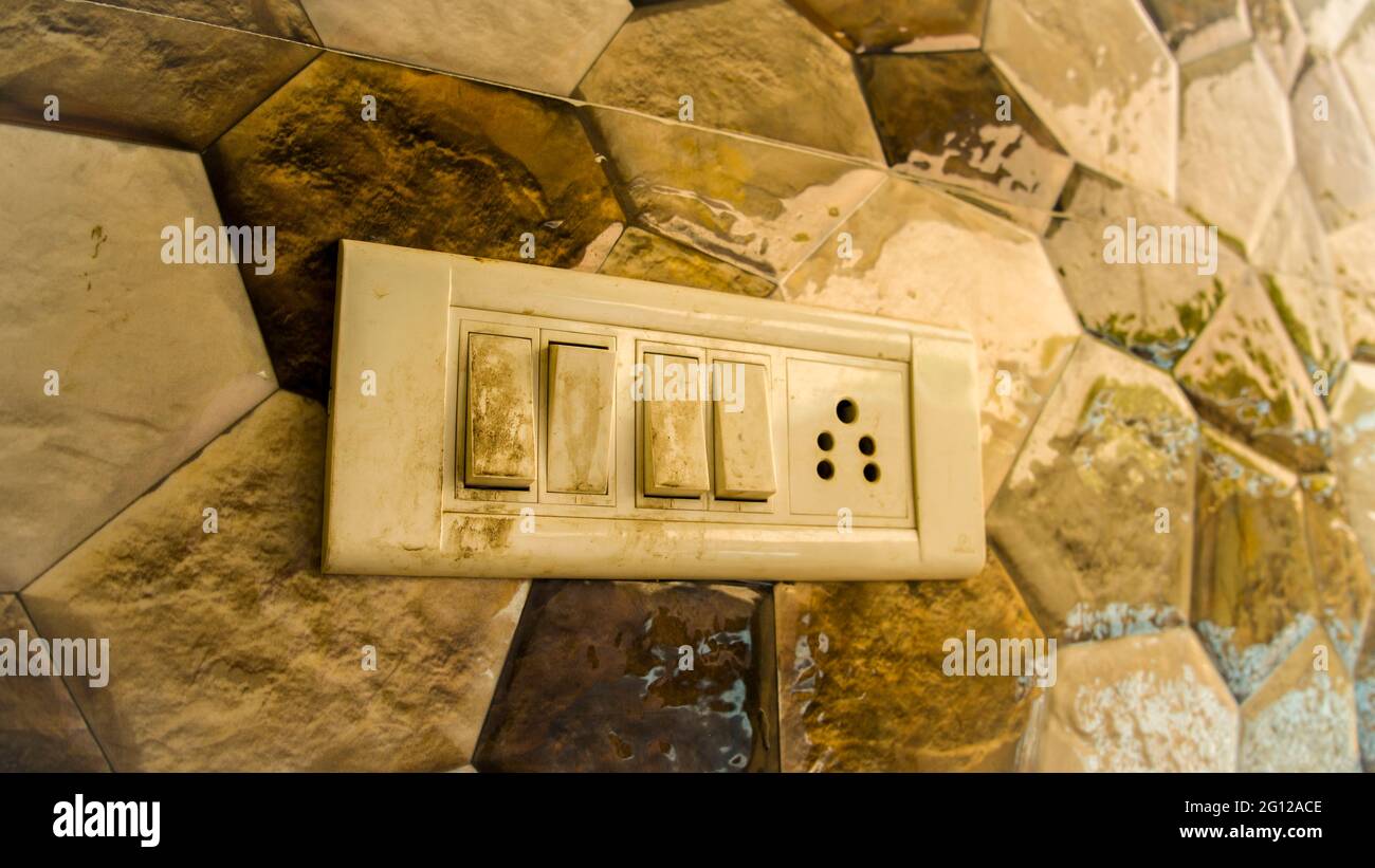 Schmutziger Strom am aus-Schalter mit bunten Fliesen Hintergrund. Alter Schalter für weißes Licht. Stockfoto