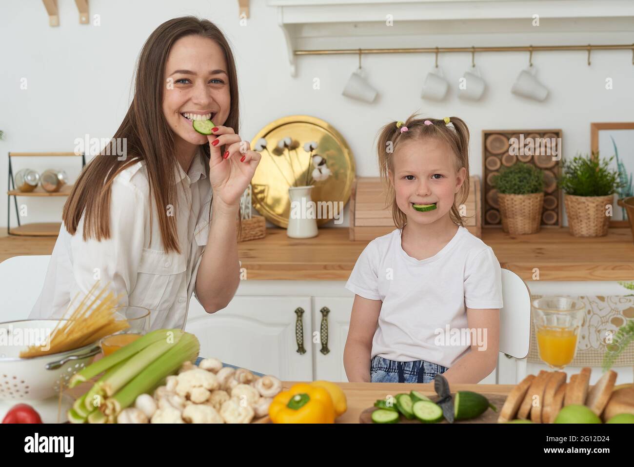 Gesunde Ernährung zu Hause. Eine fröhliche Mutter lacht, hat Spaß und umarmt ihre Tochter. Stockfoto