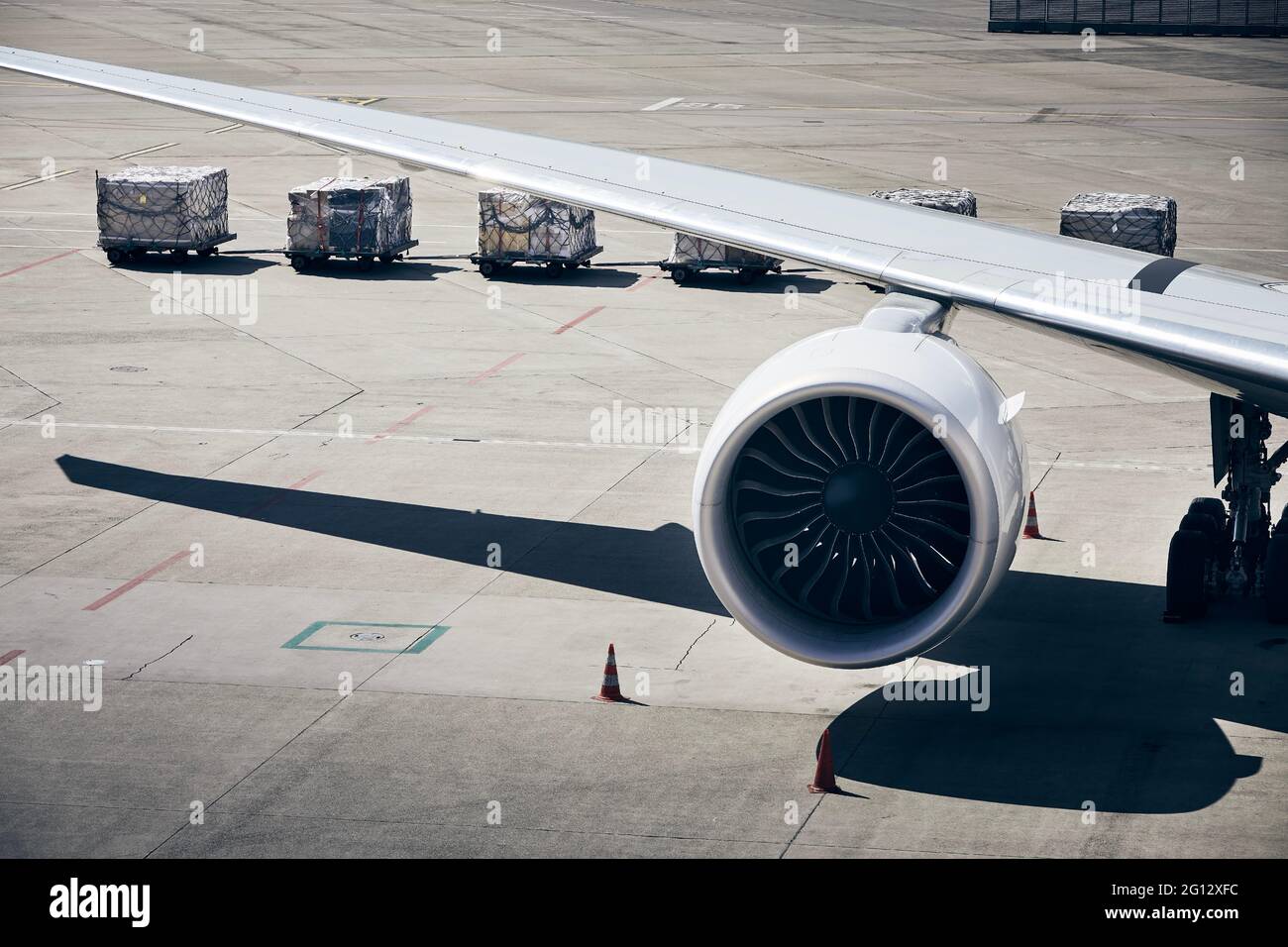 Verladung von Frachtcontainern zum Flugzeug am Flughafen. Bodenabfertigung Vorbereitung des Flugzeugs vor dem Flug an sonnigen Tagen. Stockfoto