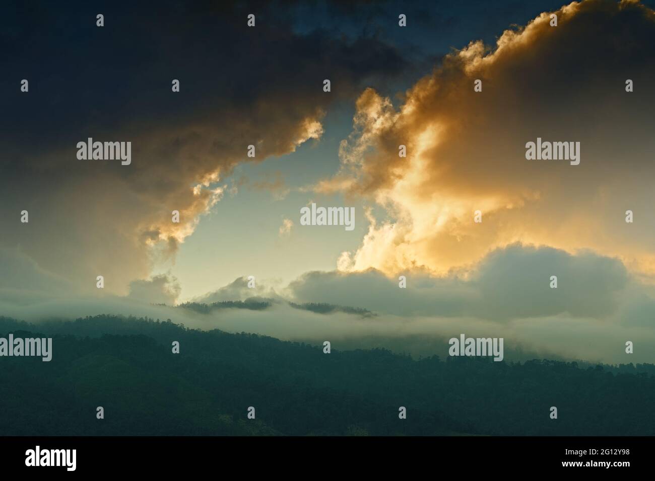 Licht, das durch das Wolkenfenster von untergehenden Sonnenstrahlen über den Gipfeln des Himalaya-Gebirges kommt. Dramatische Wolkenbildung mit Sonnenuntergangsfarben über Indian Mounta Stockfoto