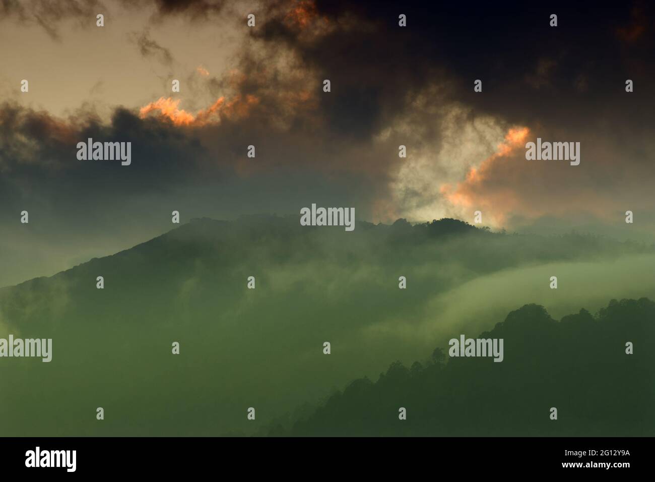 Licht, das durch das Wolkenfenster von untergehenden Sonnenstrahlen über den Gipfeln des Himalaya-Gebirges kommt. Dramatische Wolkenbildung mit Sonnenuntergangsfarben über Indian Mounta Stockfoto