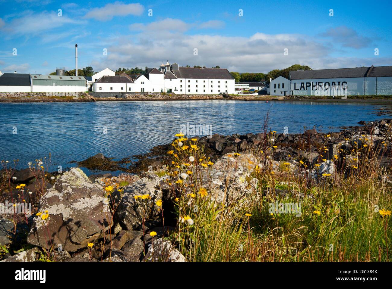 Ein Blick über die kleine Bucht zu den Gebäuden der Laphroaig Whisky-Brennerei auf der Isle of Islay in Schottland. Stockfoto