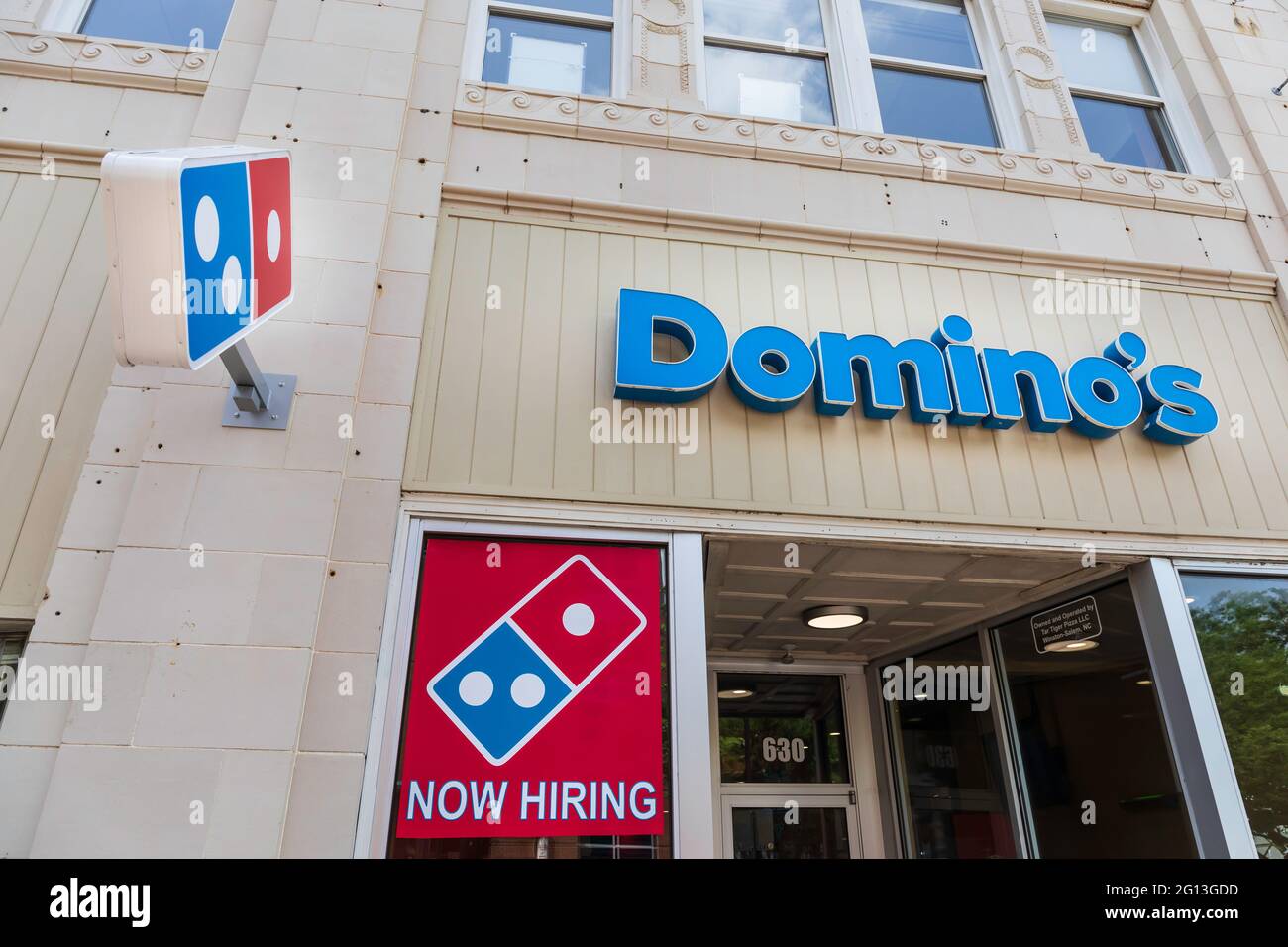 WINSTON-SALEM, NC, USA-1 JUNE 2021: Fassade von Domino's auf der 4th Street, mit 'Domino's'-Schild, Logo und 'Now Hiring'-Schild. Stockfoto