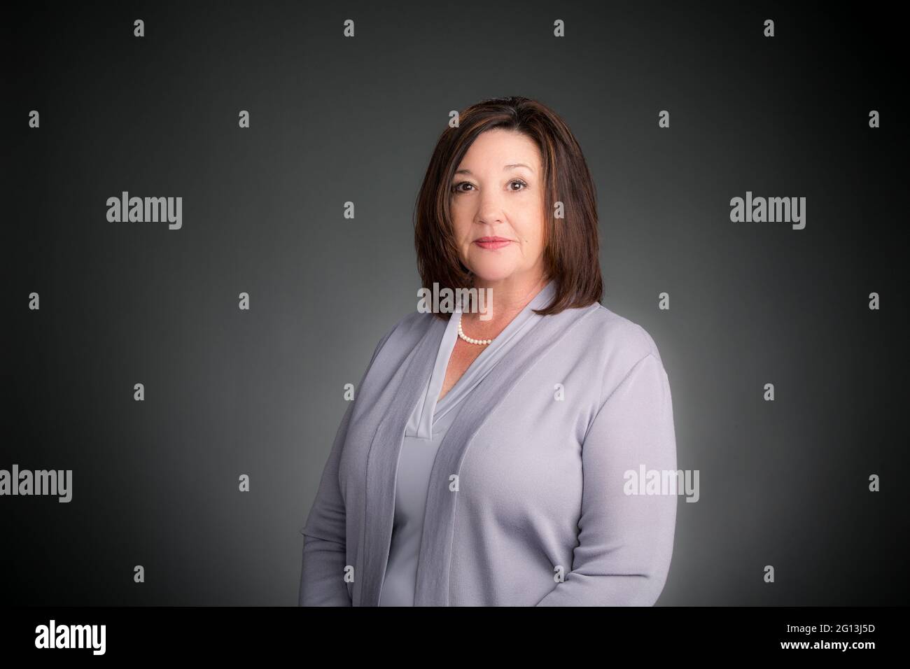 Eine seriöse Führungskraft in ihrem Unternehmensporträt, in einem Studio-Setting mit einem grauen nahtlosen Hintergrund. Stockfoto