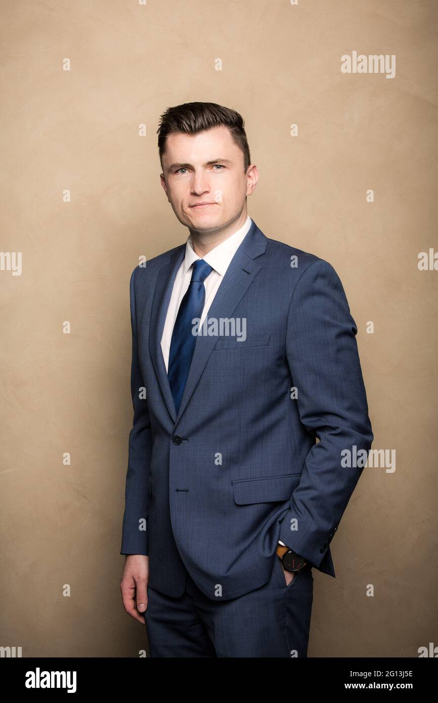 Ein junger Mann in einem Unternehmensporträt. Er lächelt nicht, als er die Kamera anschaut, trägt einen Anzug und eine Krawatte in seinem Kopfschuss. Stockfoto