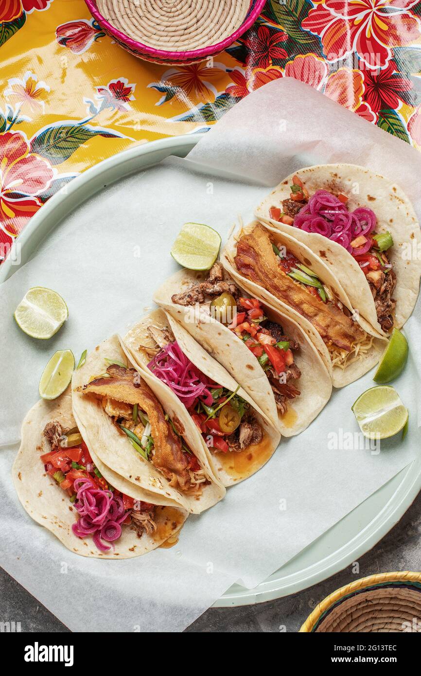 Gemischter mexikanischer Tacos mit hausgemachtem Salsa, Limes und Petersilie auf hellem traditionellem Hintergrund Stockfoto