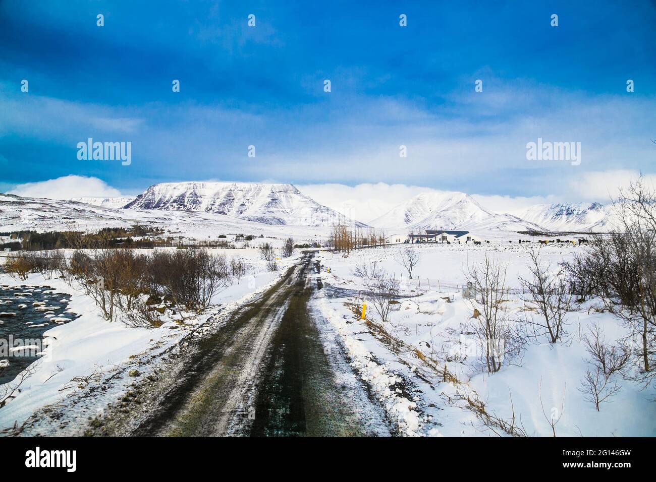 Island Road Trip, die Autobahn entlang von schneebedeckten Bergen, fantastische isländische Landschaft, malerischer Winterzeitblick, die Nacht verlagert sich auf einen Sonneneinfall Stockfoto
