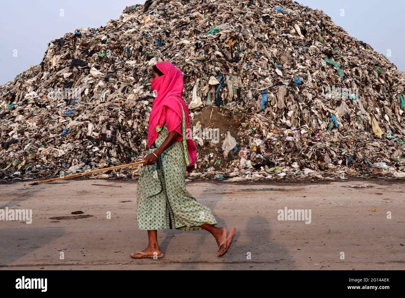 Guwahati, Assam, Indien. Juni 2021. Eine Frau, die am Vorabend des Weltumwelttages am 04. Juni 2021 in Guwahati neben einem Müllhaufen auf dem Mülldeponien-Gelände von Boragaon läuft. Der Weltumwelttag wird jedes Jahr am 5. Juni begangen, und das Thema dieses Jahres ist die Luftverschmutzung. Quelle: David Talukdar/ZUMA Wire/Alamy Live News Stockfoto