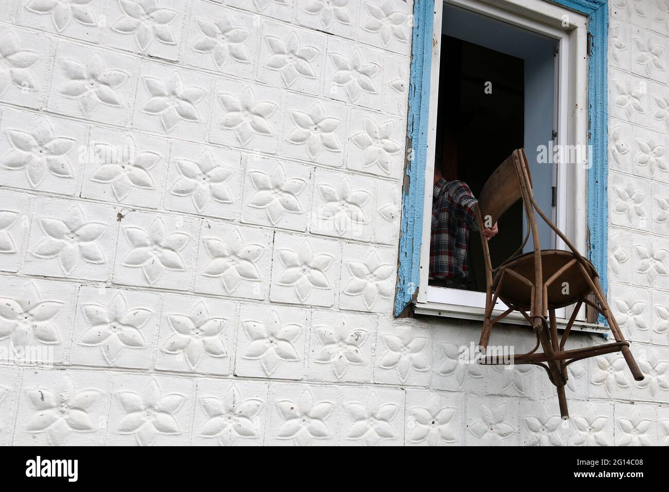Ein Mann wirft einen alten Stuhl aus dem Fenster. Tradition werfen eine alte Dinge / Stockfoto Ein Mann wirft einen alten Stuhl aus dem Fenster. Tradition werfen eine alte Dinge / Stockfoto