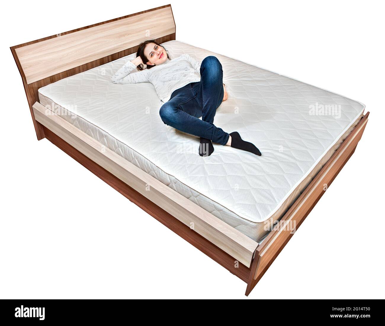 Bettgestell mit Kopfteil und Doppelmatratze, auf der die junge europäische Frau liegt. Stockfoto