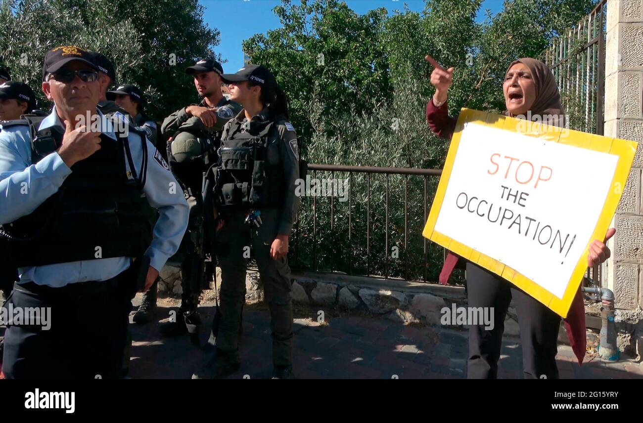 Eine Palästinenserin hält ein Plakat mit der Aufschrift „Stoppt die Besatzung“ während einer Demonstration gegen israelische Besatzung und Siedlungsaktivitäten in Scheich Jarrah, einem überwiegend palästinensischen Viertel, am 04. Juni 2021 in Jerusalem, Israel. Das palästinensische Viertel Sheikh Jarrah ist derzeit das Zentrum einer Reihe von Eigentumsstreitigkeiten zwischen Palästinensern und rechtsgerichteten jüdischen Israelis. Einige Häuser wurden nach einem Gerichtsurteil von israelischen Siedlern besetzt. Stockfoto