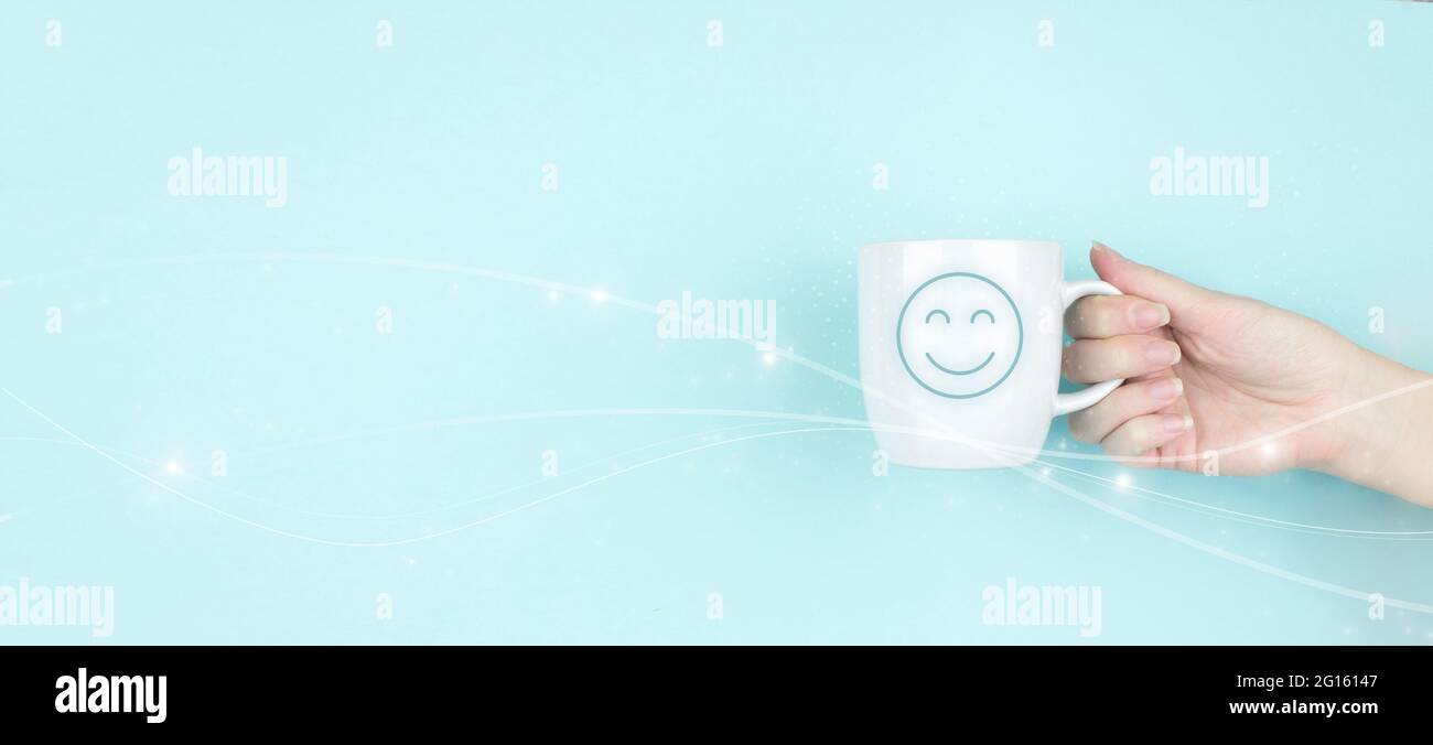 Mädchen Hand halten Morgen Kaffeetasse mit Zeichen Smiley Gesicht Symbol auf blauem Hintergrund Stockfoto