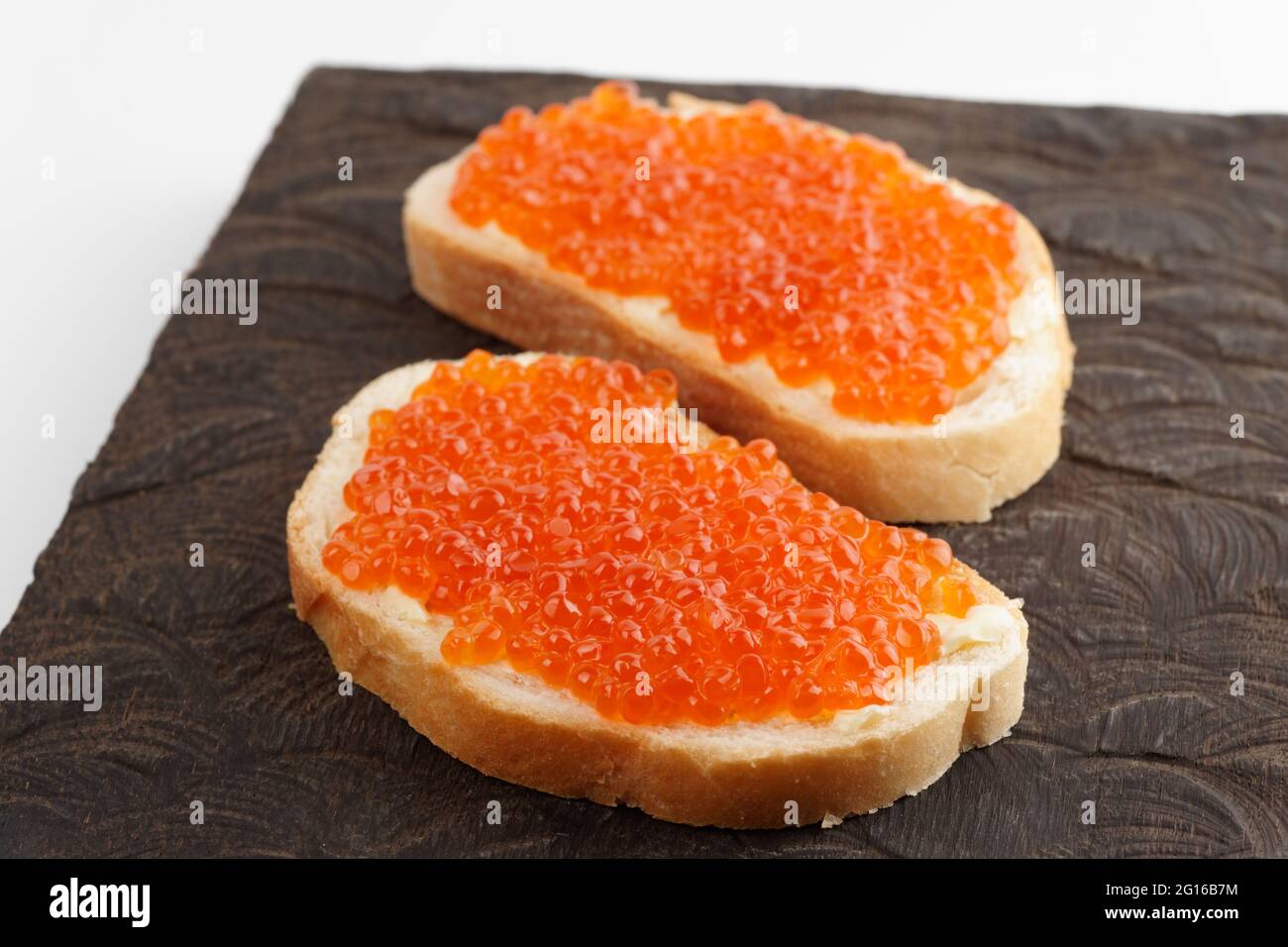 Zwei Brote mit rotem Lachsrogen auf Holzbrett Stockfoto