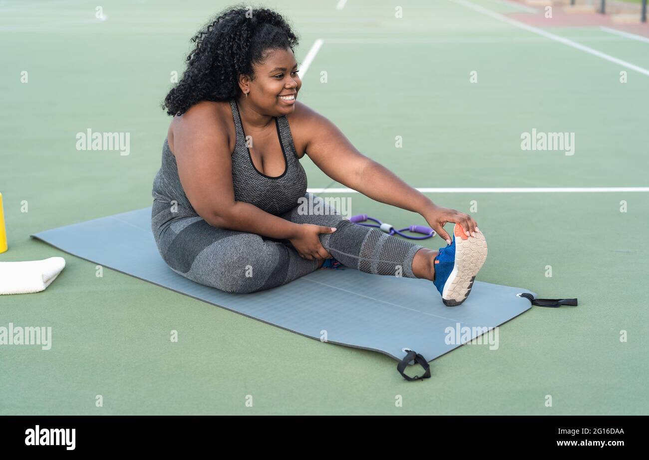 Kurvige Afro-Frau macht Stretching-Übungen - Junge afrikanische Frau hat Spaß beim Training im Freien - Sportliche Menschen Lifestyle-Konzept Stockfoto