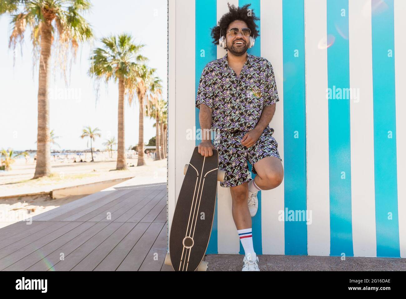 Afro-lateinischer Mann, der während der Ferien mit Kopfhörern am tropischen Strand Musik hört Stockfoto Afro-lateinischer Mann, der während der Ferien mit Kopfhörern am tropischen Strand Musik hört Stockfoto