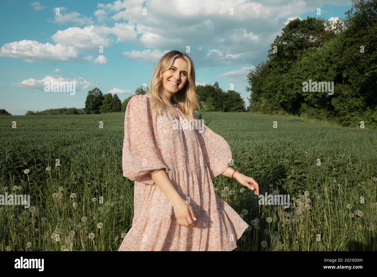 Junge Frau im grünen Feld tanzen. Konzept von Glück, Freiheit und Unabhängigkeit Stockfoto