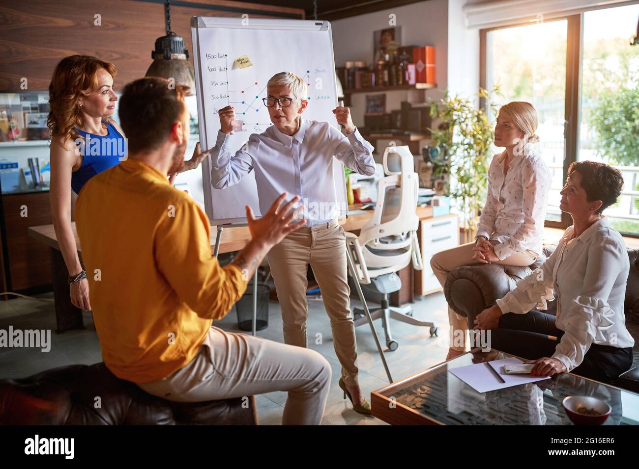 Eine ältere Chefin ist wütend auf ihren jungen männlichen Kollegen, während sie in einer angespannten Atmosphäre am Arbeitsplatz ein Treffen veranstaltet. Unternehmen, Büro, Job Stockfoto