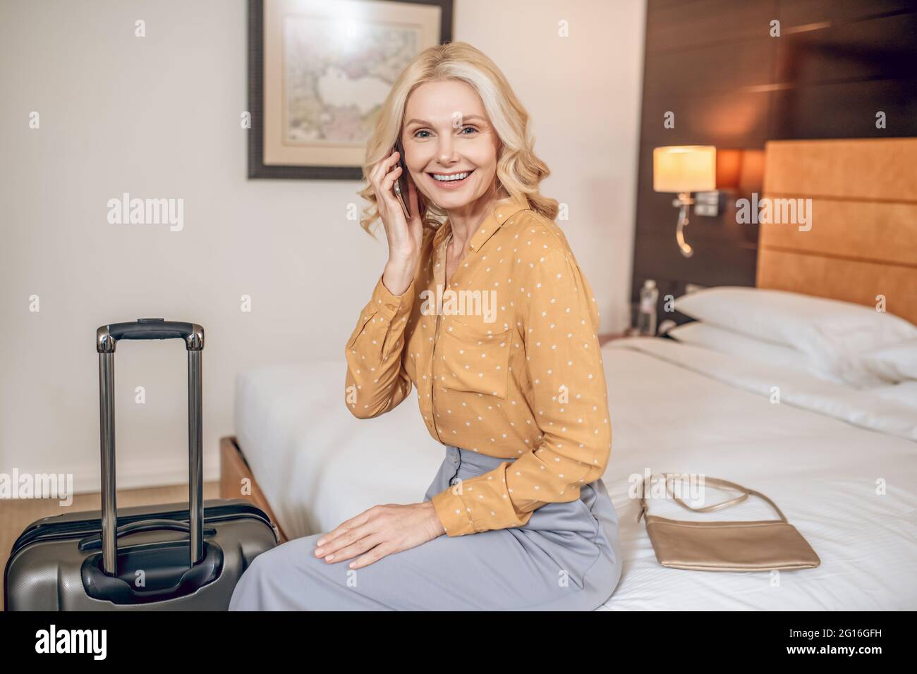 Elegante blonde Frau in grauer Hose in einem Hotelzimmer Stockfoto