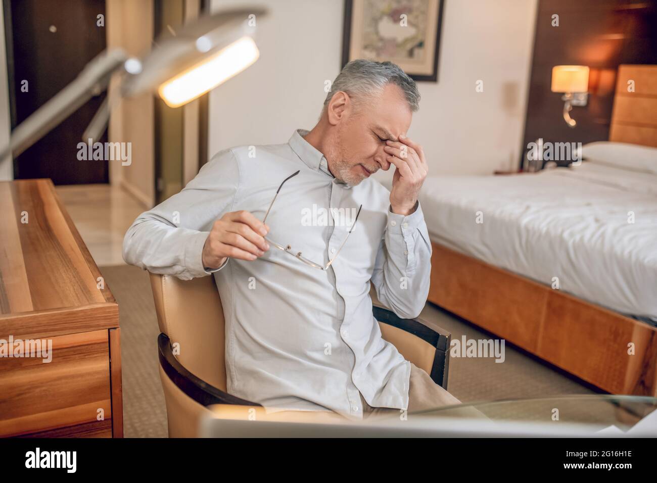 Grauhaariger Mann, der sich nach einem langen Arbeitstag müde fühlt Stockfoto