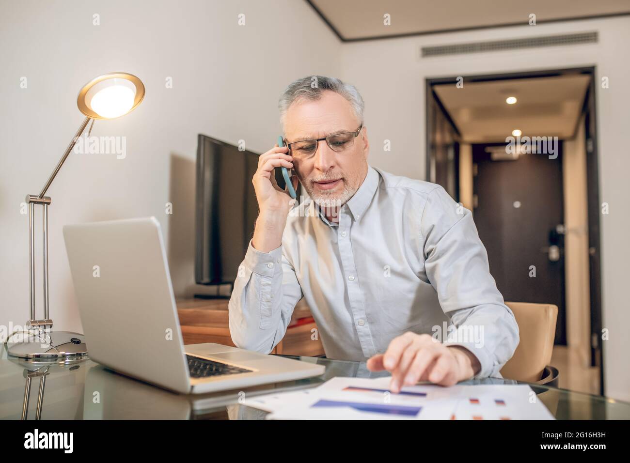 Reifer Mann, der am Telefon spricht und mitschaut Stockfoto